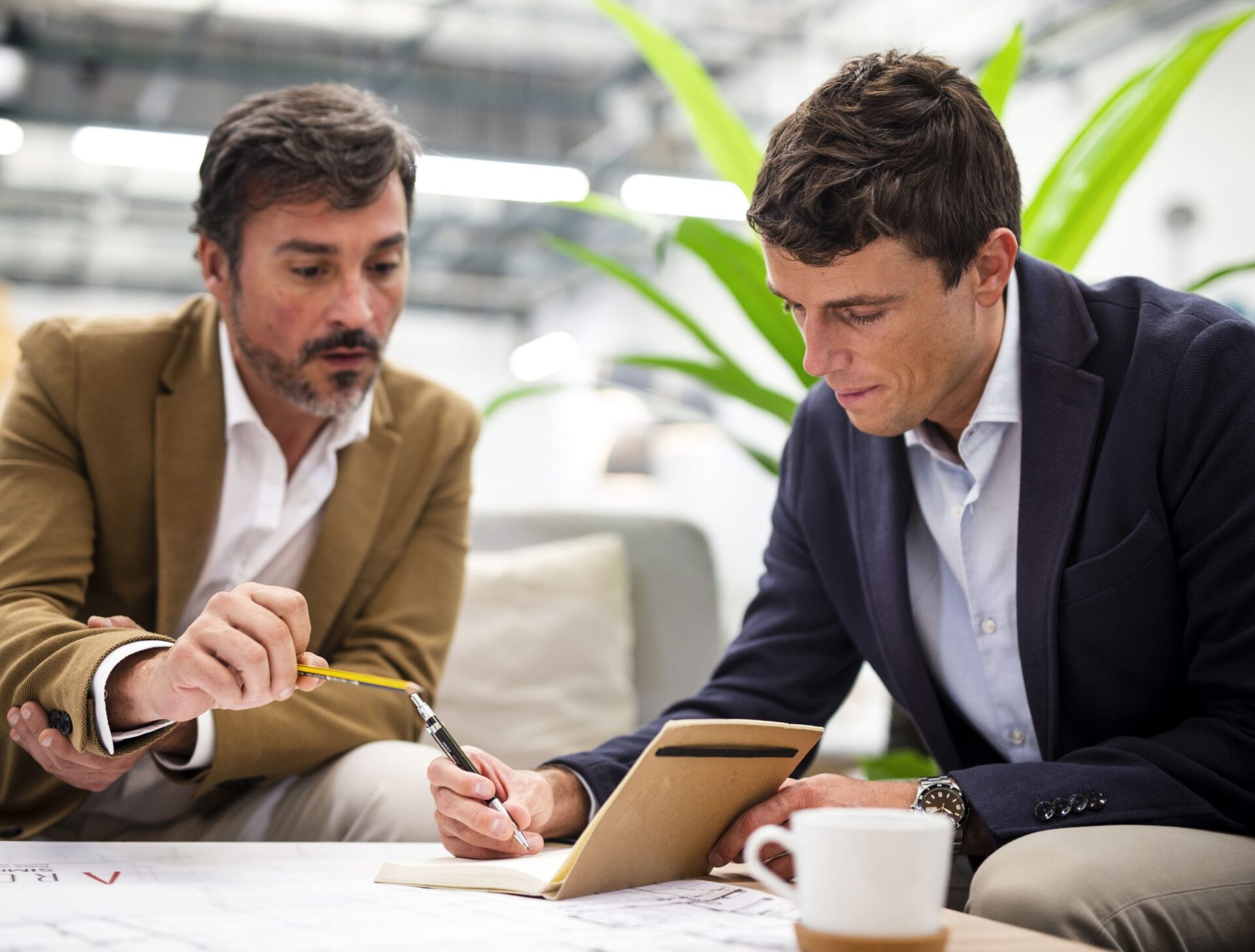 younger businessman taking notes with older businessman