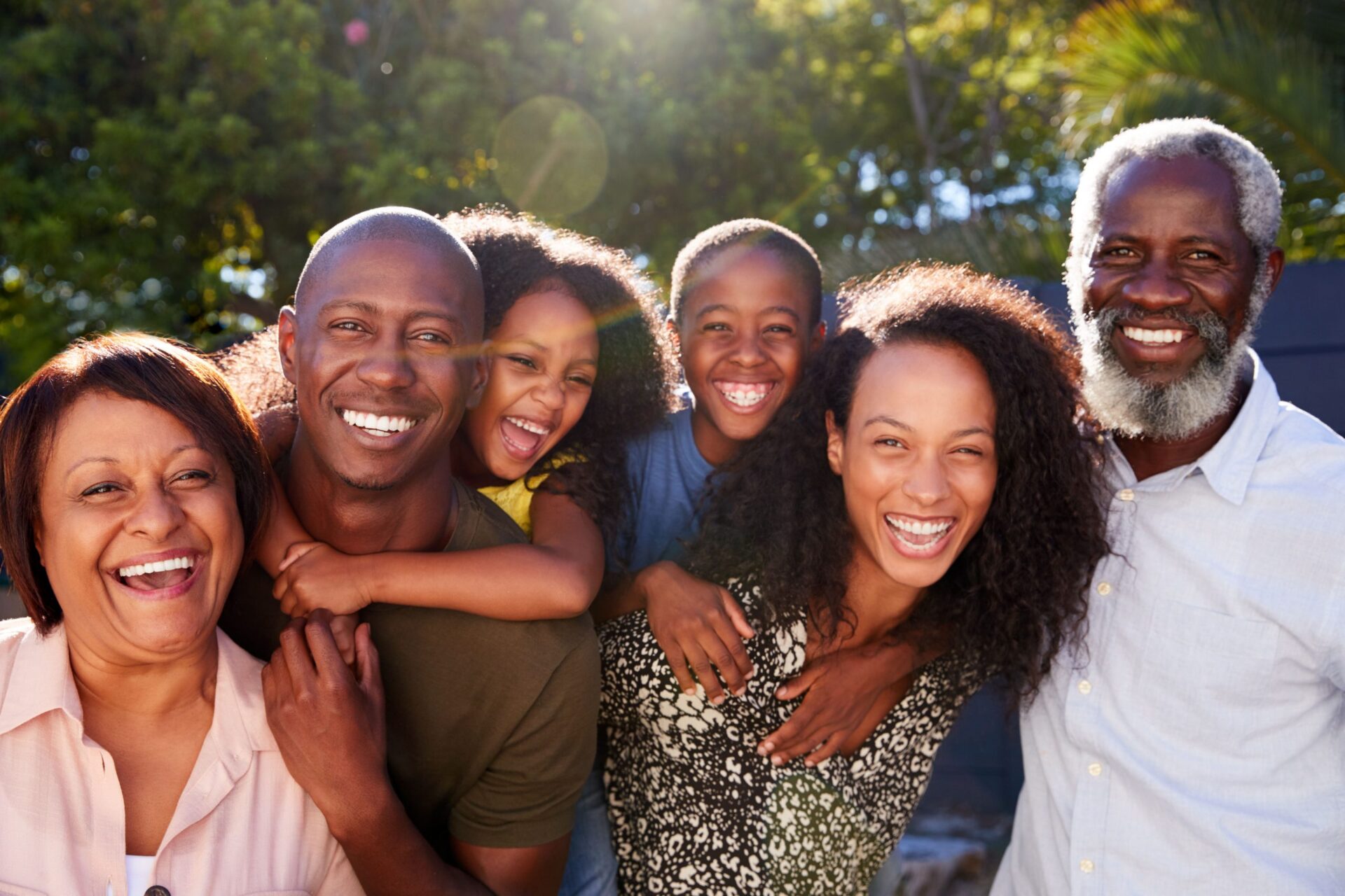 Outdoor Portrait Of Multi-Generation Family In Garden At Home Against Flaring Sun Multi-generation family portrait