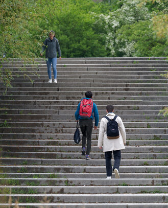 Rear view of group of students at public park of university campus of Swiss town. How 529 plans reduce the cost of higher education