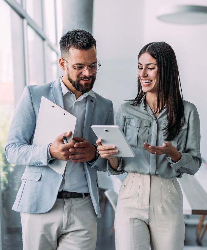 Making decisions on the move. Shot of a two confident business persons talking in the work place. Two colleagues using a digital tablet while walking in a modern office. Businessman and businesswoman in meeting discussing business strategy. Business coworkers working together in the offic